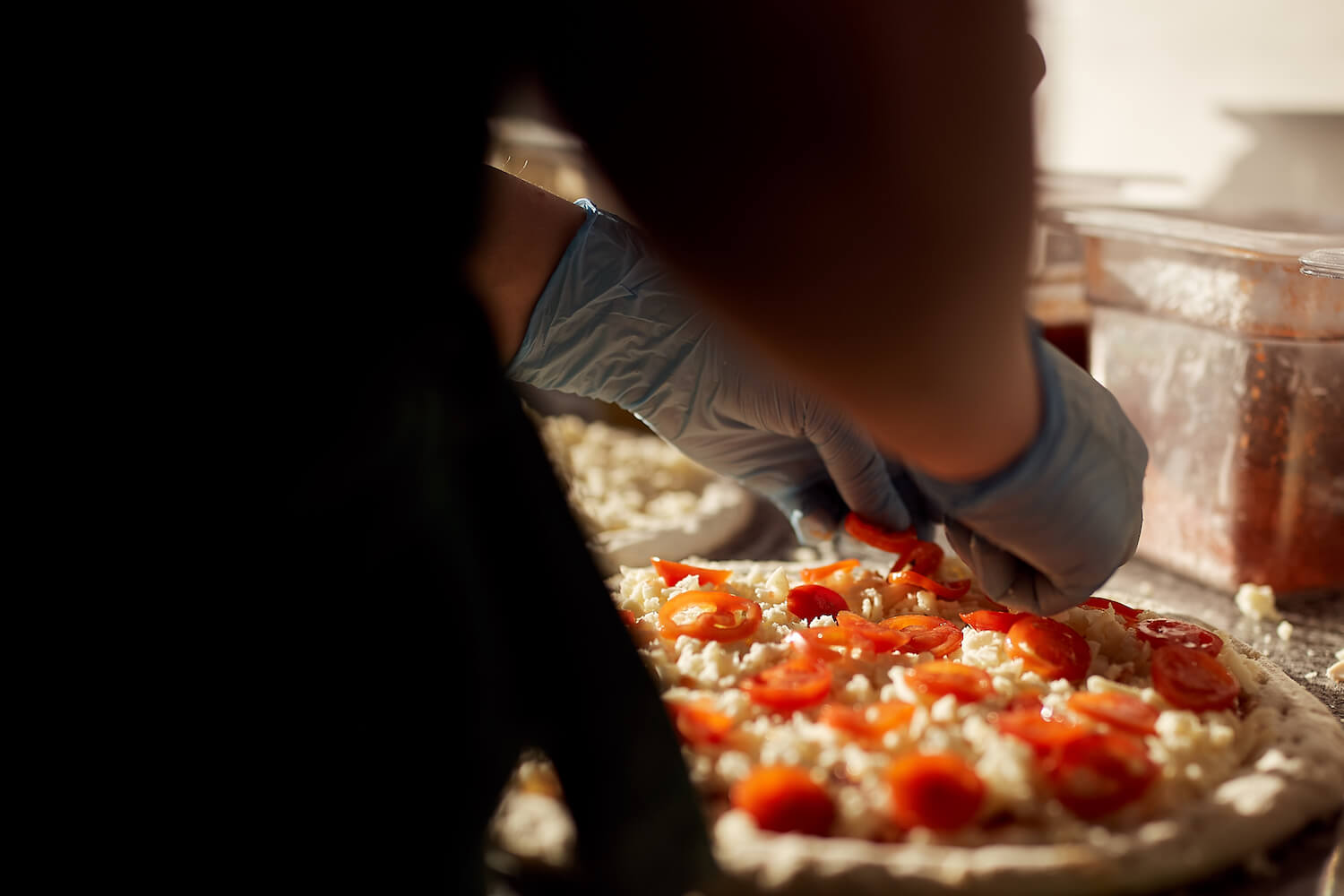 Сотрудница пиццерии «О-пицца» раскладывает помидоры на пицце