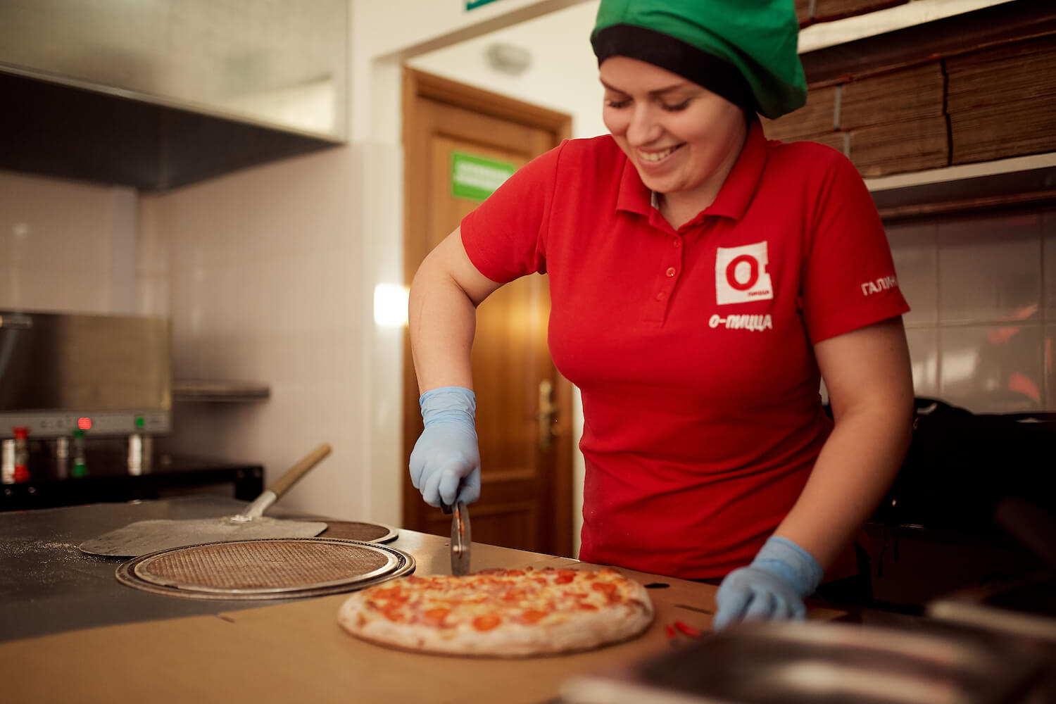 Сотрудница пиццерии «О-пицца» режет пиццу