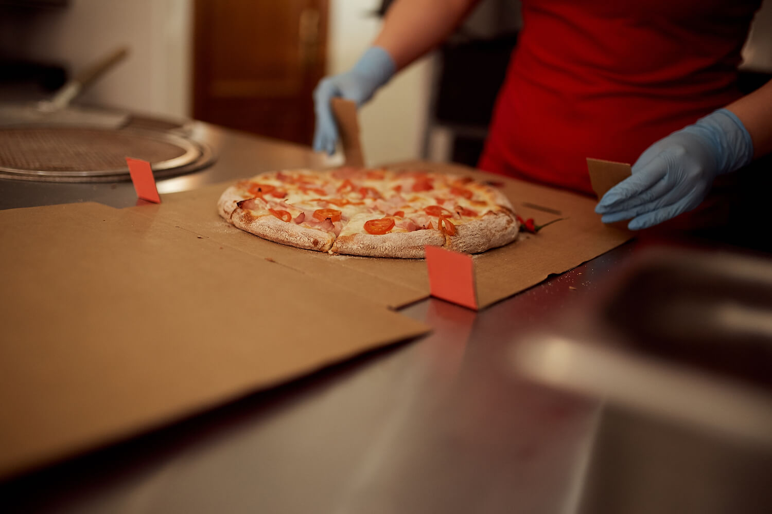 Сотрудница пиццерии «О-пицца» упаковывает пиццу в коробку