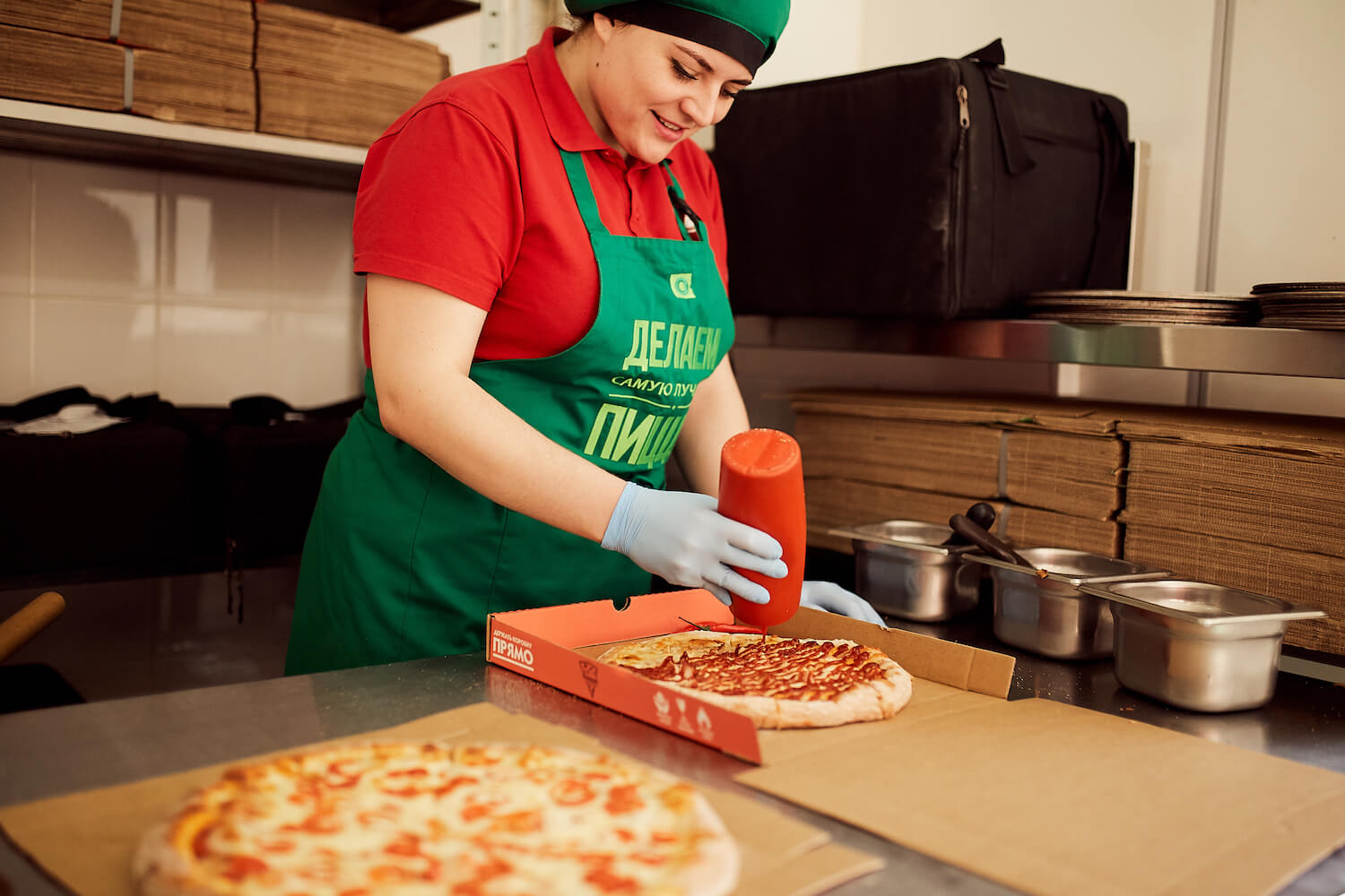 Сотрудница пиццерии «О-пицца» поливает пиццу соусом барбекю
