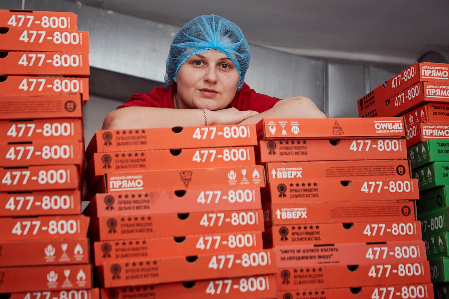 Сотрудница пиццерии «О-пицца» рядом с коробками для пиццы
